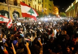 FILE - Anti-government protesters enable flashlights on their mobile phones as they shout slogans during a protest in downtown Beirut, Lebanon, Dec. 15, 2019.