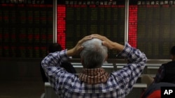 An investor reacts near boards displaying stock market prices in Beijing, China, Dec. 6, 2018. 