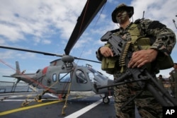 Seorang anggota Kelompok Operasi Khusus Angkatan Laut Filipina berdiri di samping helikopter di dermaga Manila, Filipina, 17 Desember 2014. (AP/Aaron Favila)