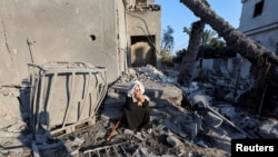 Seorang perempuan Palestina duduk di lokasi serangan Israel terhadap sebuah rumah, di tengah konflik Israel-Hamas, di Deir Al-Balah di Jalur Gaza tengah, 7 Agustus 2024.