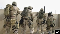 FILE - A team of U.S. Navy SEALs battles insurgents from a rooftop in Ramadi, Iraq, April 2006. Special Operations Chief Edward Gallagher pleaded not guilty Friday to allegations of shooting at Iraqi civilians and killing an Islamic State teen.