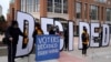 People hold signs outside the Wisconsin Center before a Milwaukee hand recount of presidential votes, in Milwaukee, Wisconsin, Nov. 20, 2020.