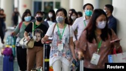 Para penumpang, sebagian besar wisatawan asing, dengan mengenakan masker tiba di terminal kedatangan bandara I Gusti Ngurah Rai, Denpasar, Bali (4/2). 