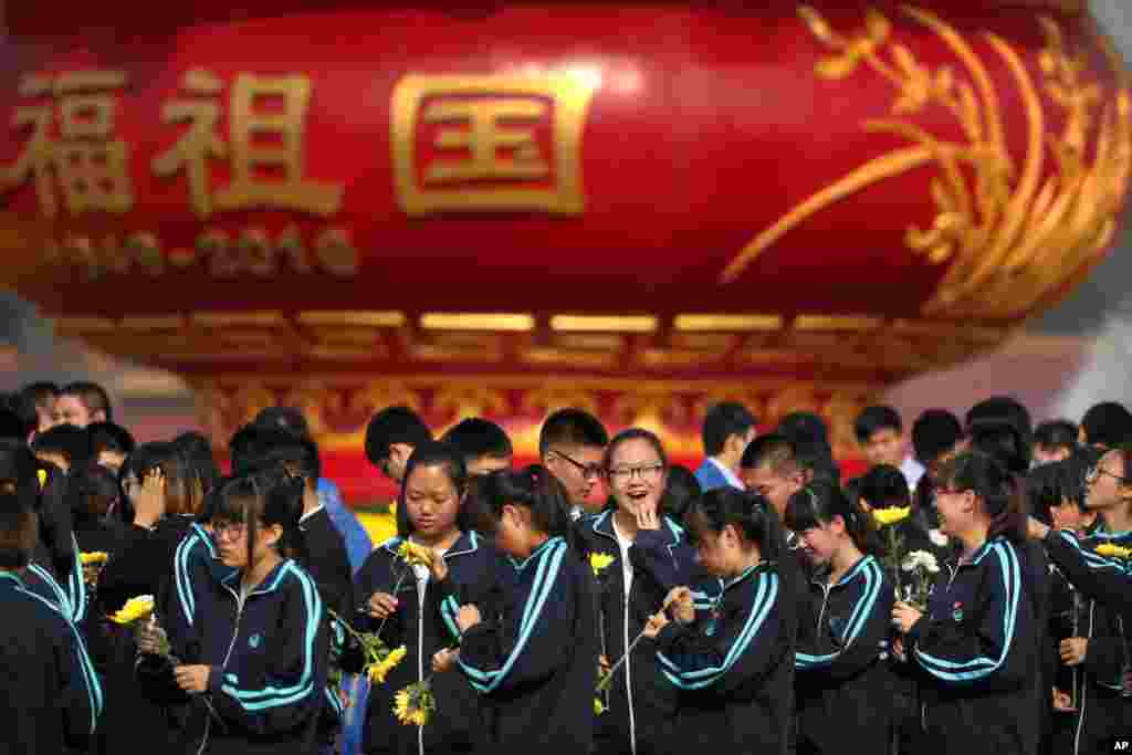 Chinese students stand near a monument commemorating the anniversary of the founding of China before a ceremony marking Martyrs' Day at Tiananmen Square in Beijing.