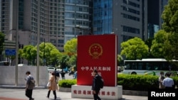 Para pejalan kaki melintas di depan papan iklan yang mempromosikan konstitusi China di sebuahjalan di Shanghai, China, 9 Mei 2023. (Foto: Aly Song/Reuters)