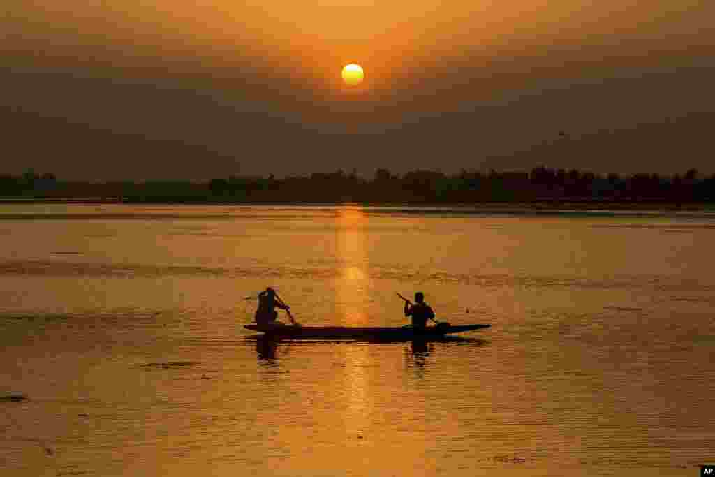 A man pulls a fishing net on a traditional boat during sunset on the Dal Lake in Srinagar, Indian-controlled Kashmir.