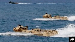 FILE - U.S. Navy amphibious assault vehicles with Philippine and U.S. troops on board are seen during joint exercises near a beach facing one of the contested islands in the South China Sea known as the Scarborough Shoal in the West Philippine Sea