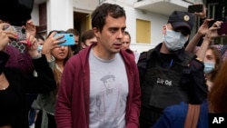 FILE - Roman Dobrokhotov, editor-in-chief of The Insider, walks surrounded by police officers and journalists, in Moscow, Russia, July 28, 2021.