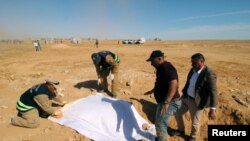 FILE - Iraqi members of the Civil Defense cover the bones from an unearthed mass grave of Kurds in west of the city of Samawah, Iraq, April 14, 2019.