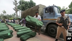 An Indian security man stands guard as a worker places a bag carrying federal budget copies for the year 2019- 20, that will be distributed to lawmakers at the parliament house in New Delhi, India, Friday, July 5, 2019. 