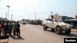 Residents watch as a U.N. Multidimensional Integrated Stabilization Mission in the Central African Republic (MINUSCA) armored personnel carrier patrols after attacks in Begoua, a northern district of Bangui, C.A.R., Jan. 13, 2021.