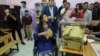 FILE - Lisa Calan, 28, who lost both her legs at an explosion, casts her vote in Diyarbakir, in Turkey's predominantly Kurdish southeast, Nov. 1, 2015. She is walking after receiving pioneering robotic surgery in Australia.