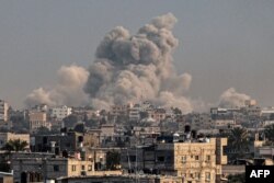 Dim se diže iznad zgrada u Kan Junisu, na jugu Pojasa Gaze, tokom izraelskog bombardovana, 15. januara 2024, na fotografiji napravljenoj iz Rafe.