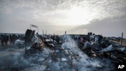فلسطینی اسرائیلی حملے کے بعد تباہی کو دیکھ رہے ہیں جہاں 27 مئی 2024 کو غزہ کی پٹی کے رفح میں بے گھر لوگ مقیم تھے۔