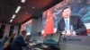 FILE - Journalists sit next to screens showing Chinese President Xi Jinping delivering a speech via video at a media center in Shanghai, Nov. 4, 2020.