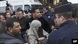 An unidentified veiled woman is taken away by plain clothed and uniformed police officers in Paris, Monday, April 11, 2011