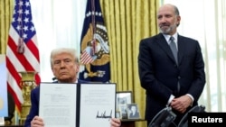 Президент Дональд Трамп тримає указ про підвищення тарифів у супроводі міністра торгівлі США Говарда Лутніка в Овальному кабінеті Білого дому у Вашингтоні, 13 лютого 2025 року. Фото: REUTERS