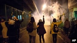 In this photograph taken Jan. 11, 2020, protesters hold flowers as tear gas fired by police rises at a demonstration in front of Amir Kabir University in Tehran, Iran, to remember victims of a Ukrainian airplane shot down by an Iranian missile.