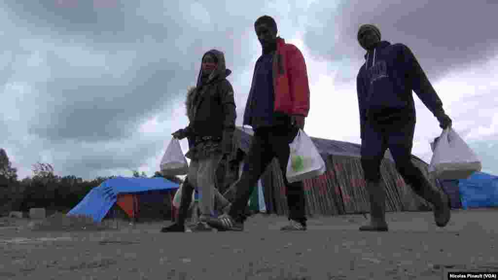 Wasu yan gudun hijira ne suke zagayawa cikin sansanin, wanda yake a wajen birnin Calais dake arewacin kasar Faransa. (Nicolas Pinault/VOA).