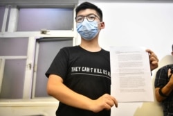 Hong Kong pro-democracy activist Joshua Wong holds up his notice for disqualification at a press conference in Hong Kong on July 31, 2020, a day after he and 11 other activists were barred from standing for election. - The prominent dissident on…