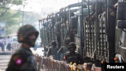 FILE- Soldiers stand next to military vehicles, in Yangon, Myanmar, Feb. 15, 2021.