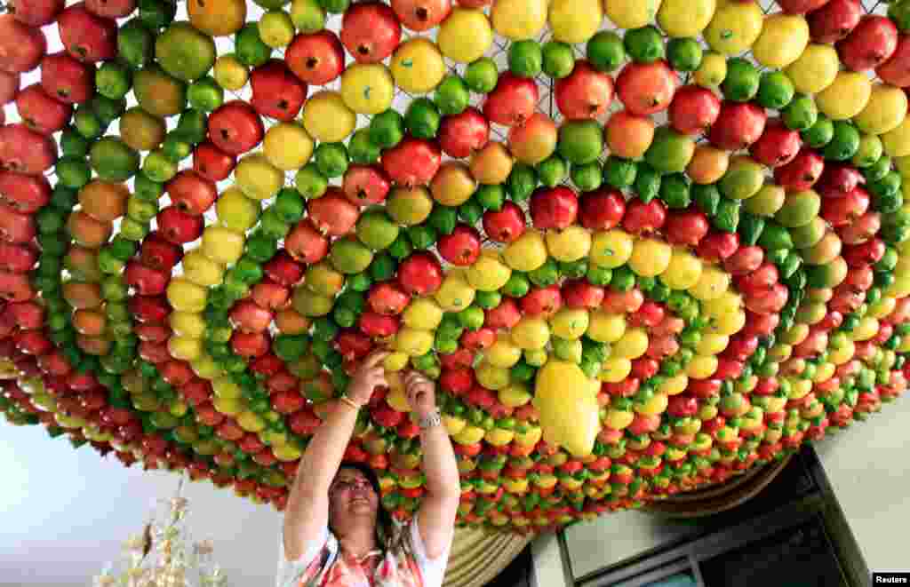 A woman from the Samaritan sect decorates a traditional hut known as a "sukkah," which is a ritual hut used during the Jewish holiday of Sukkot, with fruits and vegetables, on Mount Gerizim on the outskirts of the West Bank city of Nablus.
