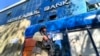 Seorang kombatan Taliban berjaga di luar sebuah bank di Kabul, Afghanistan, 13 Februari 2022. (Foto: Hussein Malla/AP Photo)