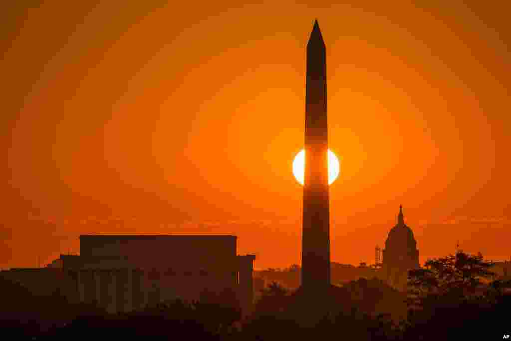 The rising sun passes behind the Washington Monument early in Washington, D.C., on what is expected to be another 90-degree day in the Nation's Capitol.