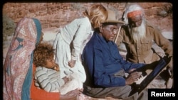 FILE - An undated photo released Oct. 14, 2017, shows family members watching Australia's most famous Aboriginal artist, Albert Namatjira, sitting on a rock as he paints.