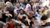 FILE - Displaced Iraqis from the Yazidi community gather for humanitarian aid at the Syria-Iraq border at Feeshkhabour border point, northern Iraq, Aug. 10, 2014.