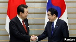 윤석열(왼쪽) 한국 대통령과 기시다 후미오 일본 총리가 16일 도쿄에서 악수하고 있다. 