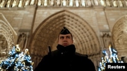 Francuski žandarm na straži. Jake policijske snage obezbeđuju prilaze katedrali Noterdam tokom proslave Božića u Parizu (REUTERS/Christian Hartmann - RTX2WDZR)