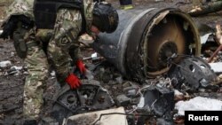 Seorang anggota unit bom memeriksa sisa-sisa rudal yang tidak teridentifikasi di lokasi di mana bangunan-bangunan penduduk rusak berat akibat serangan misil Rusia di Kharkiv, Ukraina, 2 Januari 2024. (Foto: Sofia Gatilova/Reuters)