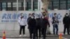 Petugas keamanan berpakaian preman berdiri di luar Pusat Pengendalian dan Pencegahan Penyakit Wuhan sebelum tim WHO tiba untuk melakukan kunjungan di Wuhan, provinsi Hubei China tengah, Senin, 1 Februari 2021. 