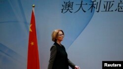 FILE - Australia's Prime Minister Julia Gillard walks past a Chinese national flag as she arrives at a welcoming lunch during the Australia China Economic and Trade Forum at a hotel in Beijing, April 9, 2013. The Chinese characters read, "Australia." 