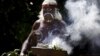 FILE - An aboriginal elder performs a ceremony during an official function at Sydney Harbor, Australia, Nov. 27, 2013. A new map documents massacres of aboriginees following the arrival in Australia of British colonists in the late 18th century.