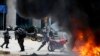 A police officer drops a privately owned motorcycle into the flames of a fire resulting from an explosion, at Altamira Square during clashes with anti-government protesters, in Caracas, Venezuela, July 30, 2017.