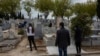 Relatives wearing face masks to protect against coronavirus observe social distancing guidelines during a burial at a Madrid cemetery during the coronavirus outbreak in Madrid, Spain, March 27, 2020.
