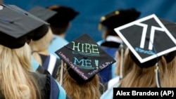 Graduates, including one looking for a job, are seated during George Washington University's commencement exercises on the National Mall, Sunday, May 17, 2015 in Washington, DC.