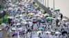 Para jemaah haji membawa payung untuk melindungi dari terik matahari, tiba di pemondokan jemaah, tenda Mina, di tengah pelaksanaan ibadah Haji di dekat Makkah, Jumat, 14 Juni 2024. (Foto: Fadel Senna/AFP)