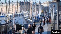 Warga swedia menikmati cuaca cerah di musim dingin dengan berjalan-jalan di sepanjang dermaga Standvagen, di tengah pandemi COVID-19 yang terus meningkat di Stockholm, Swedia, 20 November 2020. 