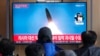 18일 한국 서울역 이용객들이 북한 탄도미사일 발사 TV 뉴스를 시청하고 있다.