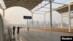Seorang pria yang memakai masker wajah setelah wabah virus Covid-19 mengambil gambar di platform Stasiun Kereta Shijiazhuang di Shijiazhuang, Provinsi Hebei, China 22 Januari 2021. (Foto: REUTERS/Martin Pollard)