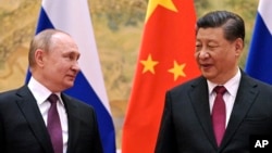 FILE - Chinese President Xi Jinping, right, and Russian President Vladimir Putin talk to each other during their meeting in Beijing, China on Feb. 4, 2022.