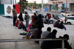 Migrants recently expelled from the U.S. after trying to seek asylum sit next to the international bridge in the Mexican border city of Reynosa, March 27, 2021.