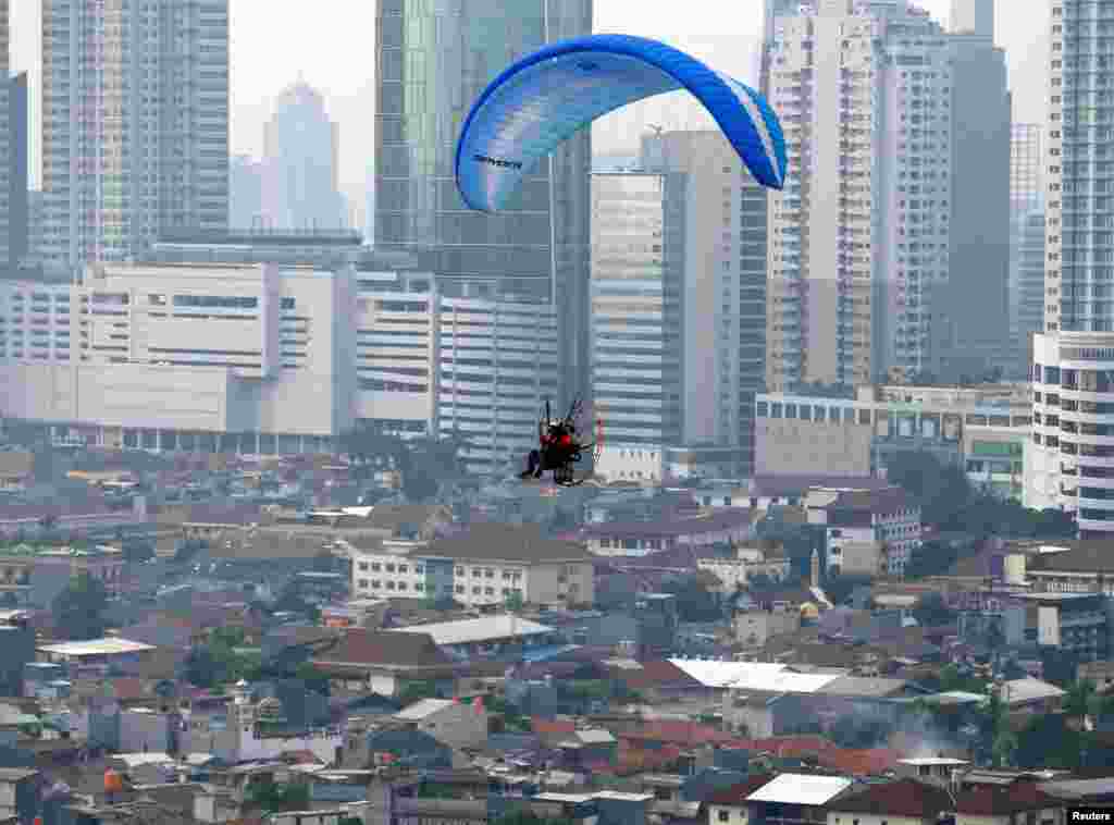 A pilot guides his powered-paraglider while flying above central Jakarta, Indonesia.