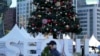 Seorang pria mengenakan masker, berjalan di depan dekorasi Natal dan pajangan logo ibu kota Korea Selatan Seoul di Seoul, Korea Selatan, Rabu, 1 Desember 2021. Lonjakan harian infeksi virus corona di Korea Selatan melebihi 5.000 untuk pertama kalinya sejak awal pandemi.