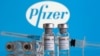 FILE - Vials labelled 'COVID-19 Coronavirus Vaccine' and a syringe are seen in front of the Pfizer logo in this illustration taken Feb. 9, 2021.