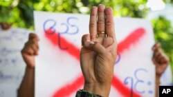 An anti-coup protester shows the three fingered salute of resistance during a strike walk with slogans to show their disaffection for military coup at neighborhood area of Hlaing township in Yangon, Myanmar, Friday, April 9, 2021. Threats of lethal…