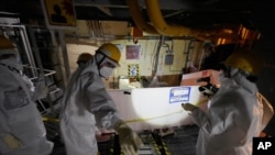 Employees of Tokyo Electric Power Company Holdingstake AP journalists to the area under the Unit 5 reactor pressure vessel, which survived the earthquake-triggered tsunami in 2011, at the Fukushima Daiichi nuclear power plant in Futaba town, northeastern Japan, on Feb. 20, 2025. 
